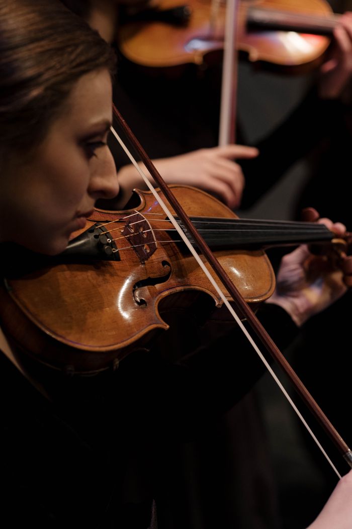 A female violinist playing passionately during an indoor concert performance.